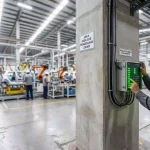 Insinyur jaringan memantau indikator lampu hijau pada kotak switch fiber optic pabrik manufaktur otomotif