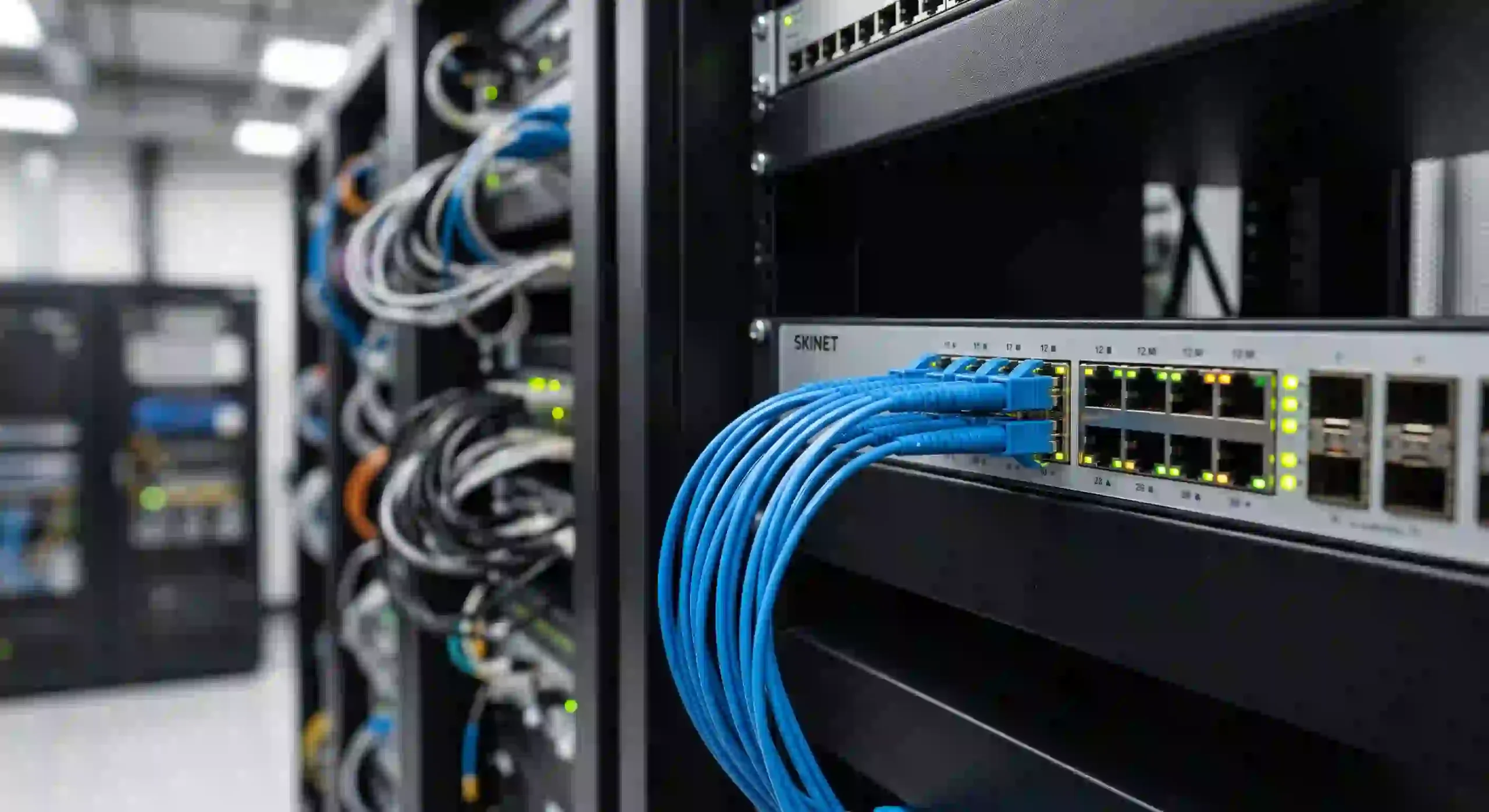 Tangkapan layar resolusi tinggi jepretan kamera dari jarak dekat memperlihatkan kabel transmisi data fiber optik berwarna biru menyala menancap ke mesin sakelar perute utama perusahaan Tangkapan layar resolusi tinggi jepretan kamera dari jarak dekat memperlihatkan kabel transmisi data fiber optik berwarna biru menyala menancap ke mesin sakelar perute utama perusahaan